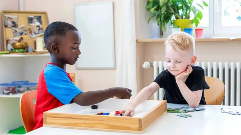 Zwei Kinder spielen gemeinsam an einem Tisch in einer Betreuungseinrichtung